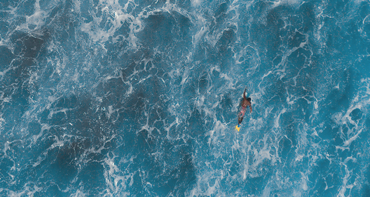 Drönarbild på en person (surfare?) som befinner sig ensam på ett stort öppet hav.