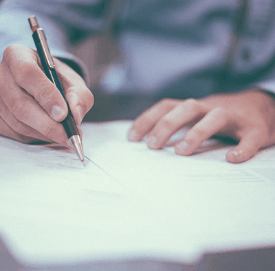Närbild på en affärsman som håller i en reservoarpenna och skriver på ett papper.